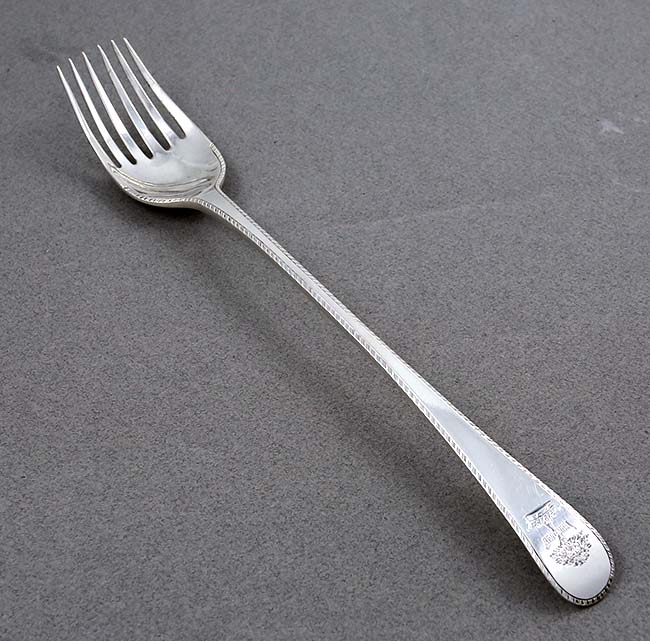 Long English silver serving fork with crest